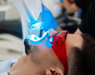 Dentist is whitening teeth of his patient with ultraviolet stomatology hardware. Teeth ultraviolet whitening process